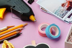 Crafting supplies arranged on a pink background, including glue gun, scissors, and decorative items for DIY projects photo