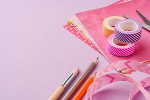 Scissors and decorative tape on colorful craft paper in a bright workspace photo