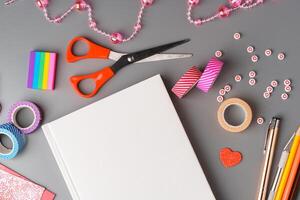 Crafting supplies arranged for a DIY project on a gray table with scissors, washi tape, and decorative items photo