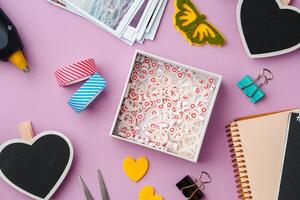Crafting supplies arranged on a pink background, including glue gun, scissors, and decorative items for DIY projects photo