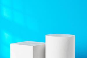 White geometric shapes on a clean surface against a bright blue background with soft shadows photo