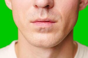Close-Up of a Young Man's Face With Green Background Displaying Distinct Expression photo
