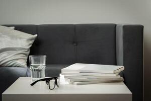Eyeglasses with stack of books, and the glass of water on the table photo