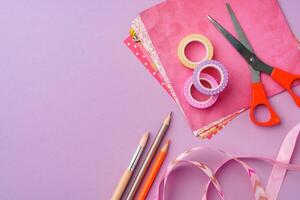 Scissors and decorative tape on colorful craft paper in a bright workspace photo