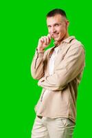 Young Man in Casual Attire Posing Thoughtfully Against a Bright Green Background photo