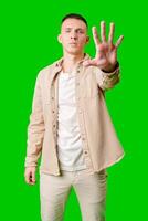 Man Holding Up Hand Against Bright Green Background While Displaying Serious Expression photo