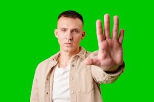 Man Holding Up Hand Against Bright Green Background While Displaying Serious Expression photo