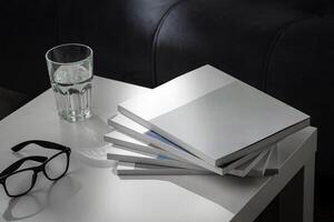 Eyeglasses with stack of books, and the glass of water on the table photo