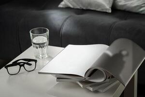 Eyeglasses with stack of books, and the glass of water on the table photo
