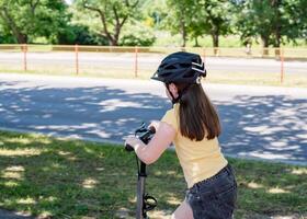 Girl rides a scooter along bicycle paths in the city in the summer. photo