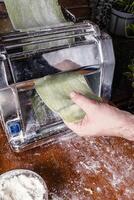 Man rolling out pasta to make spinach ravioli. photo