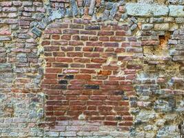 View of a very old brick wall in which a window has been bricked up. photo