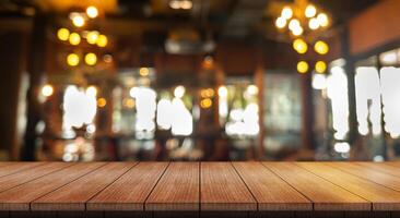 Empty wooden table top with lights bokeh on blur restaurant background. photo
