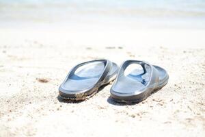 flip flops on the sand at the beach with sea background photo