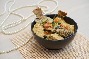 Fried fish with curry in a bowl on a bamboo mat. photo