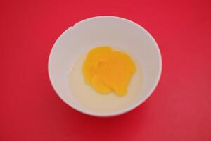 Egg yolks in a white bowl on a red background photo