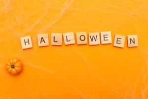 the inscription halloween sale with little pumpkin on orange background with spider web photo