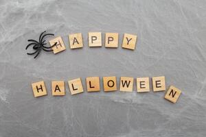 the inscription happy halloween with spider web and spiders on a gray background photo