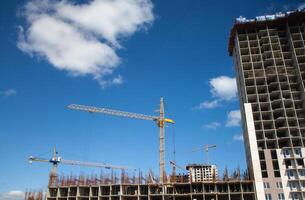 Construction site with multiple tall cranes working on building a high-rise structure under a clear blue sky photo