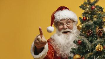 Santa looks out from behind the tree on a yellow background. photo