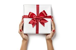 Female hands holding white gift box with red ribbon isolated on white background. photo