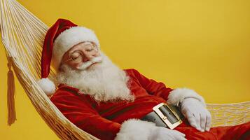 Santa Claus is resting in a hammock on a yellow background. photo