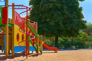 Summer children's playground with painted toy slide in public park photo
