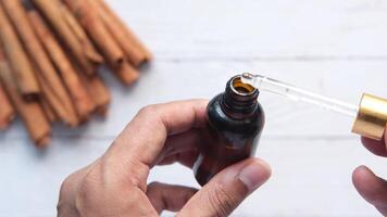 A person is holding a bottle of essential oil and cinnamon sticks video