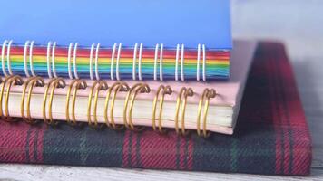 A stack of colorful notebooks with a spiral ring video