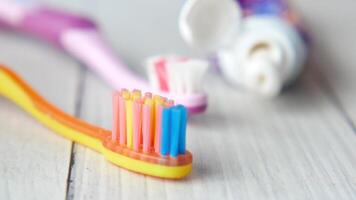 Two toothbrushes with colorful toothpaste on a wooden surface video