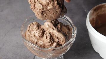 A person scooping chocolate ice cream into a glass video