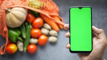 Man holding smartphone with green screen and vegetables on the background video