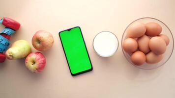 The green screen is on the left side of the table and the phone is on the right side video