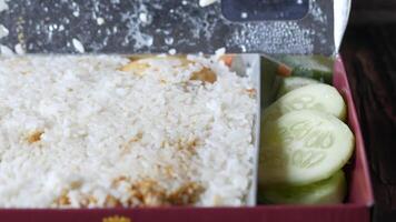 A box with rice and cucumbers sitting on top of a wooden table video