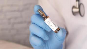 A doctor holding a small vial of a vaccine video