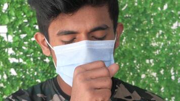 A man wearing a face mask while standing in front of a green background video