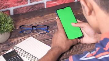 Man using smartphone with green screen on wooden table video