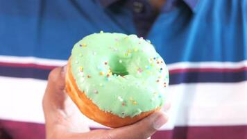 A man holding a green frosted doughnut video