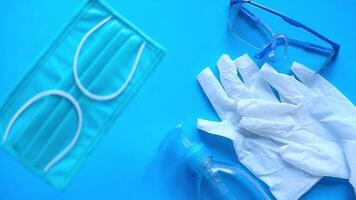 Gloves, glasses, and a bottle of hand sanitizer on a blue surface video
