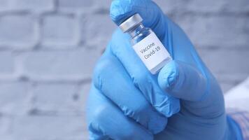 A person in blue gloves holding a vial with a label on it video