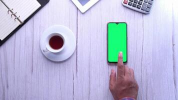 Hands on desk with green screen and smartphone video