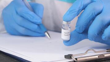 A person in blue gloves holding a vial of a vaccine video