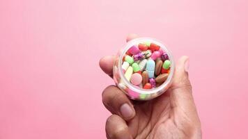A person holding a container full of colorful pills video