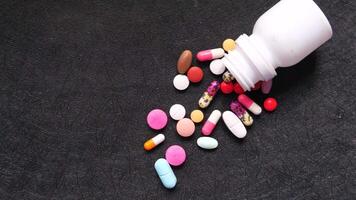 Pills spilling out of a bottle on a black surface video