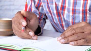 A man is writing in a notebook with a red pen video