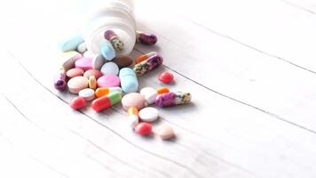 Pills and pills spilling out of a bottle on a wooden surface video