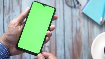Man holding a smartphone with a green screen video