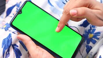 A person is using a smartphone with a green screen video