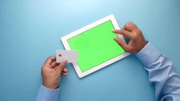 Man holding tablet with green screen and credit card on blue background video