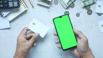 Man holding smartphone and credit card with green screen on table video